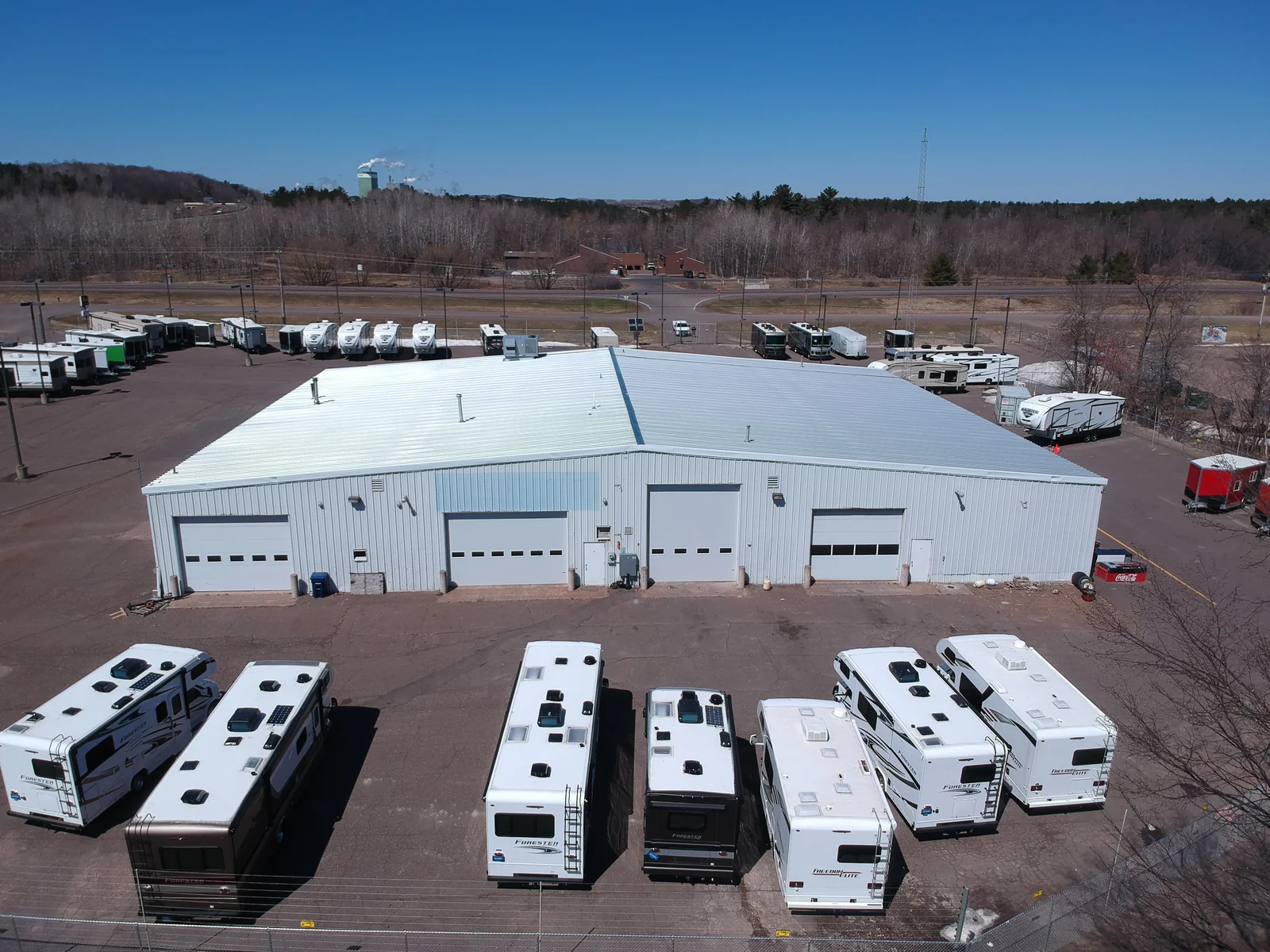 Wide shot of the dealership with the white metal roof and rows of RVs out front