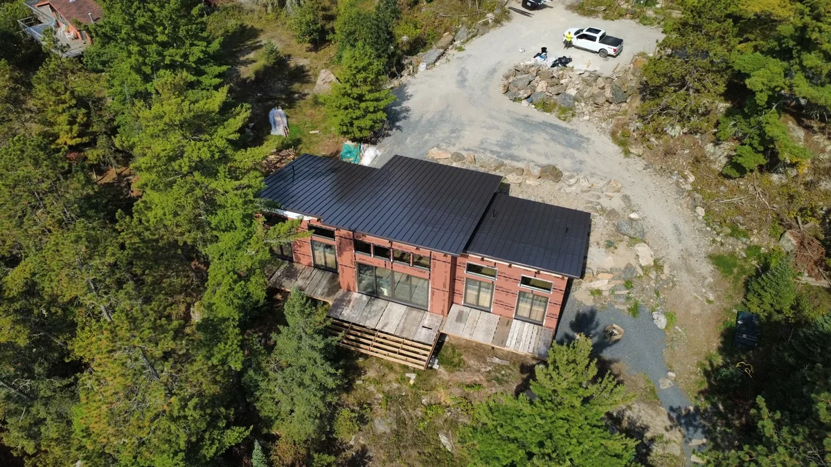 Angled aerial of the charcoal metal roof on the rustic wood-sided house