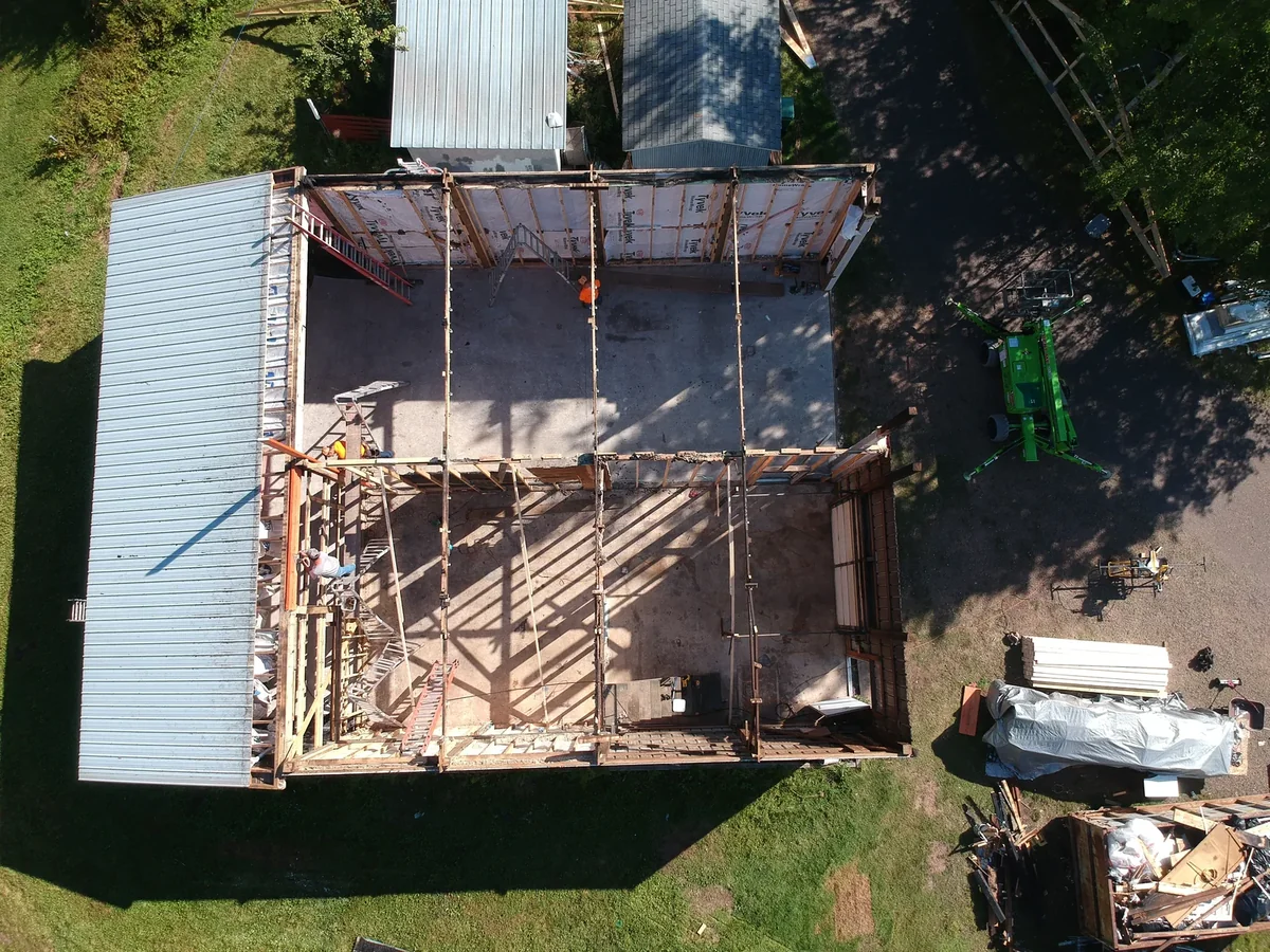 Overhead shot of the pole barn mid-rebuild with framing exposed and new white metal panels going on