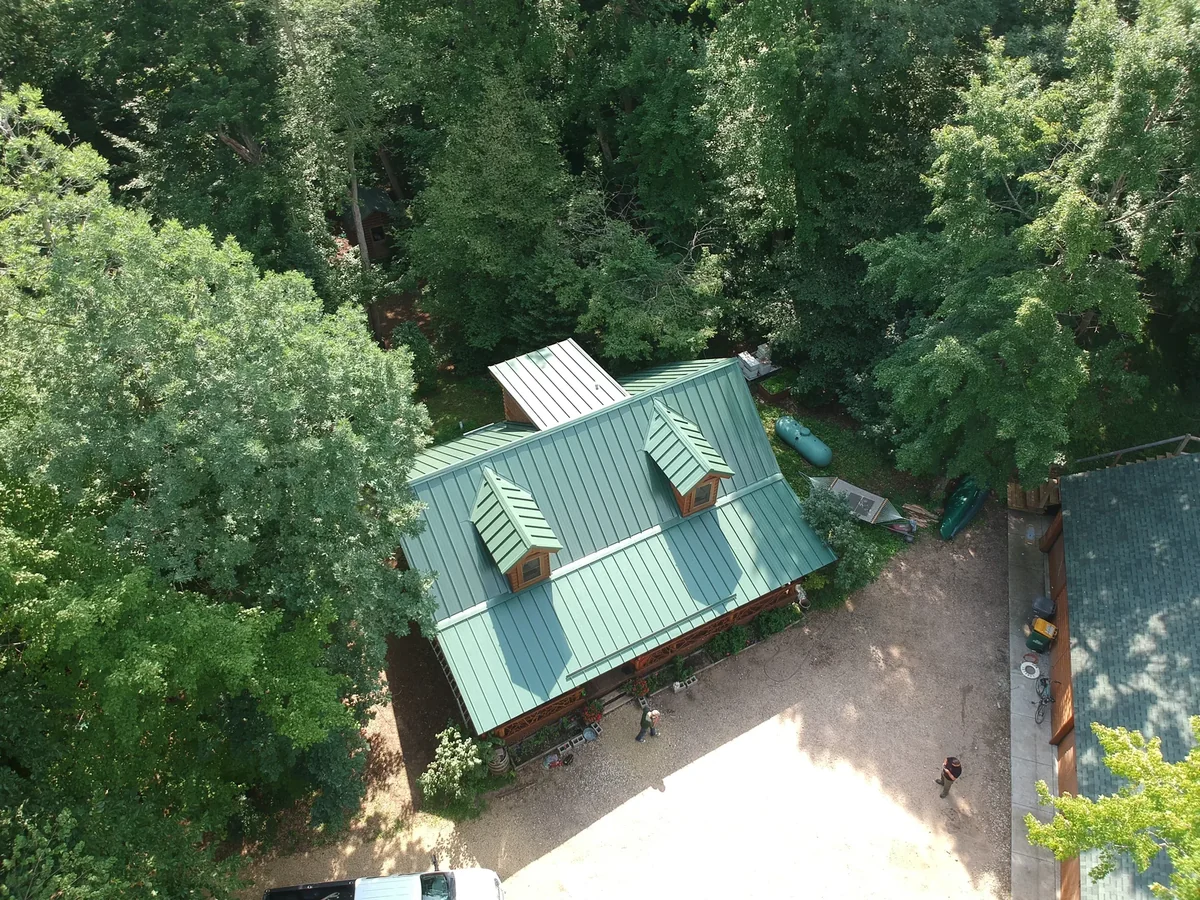 Angled aerial of the green metal roof with the driveway and yard below.