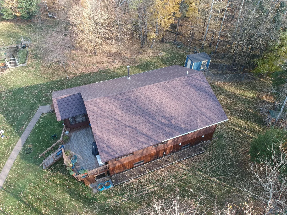 Side angle of the home showing the brown shingle roof and board-and-batten siding.