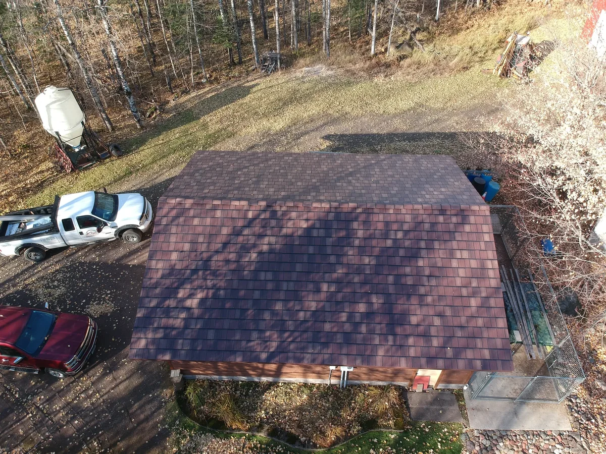 Closer overhead look at the brown metal shingle roof and the gravel driveway.