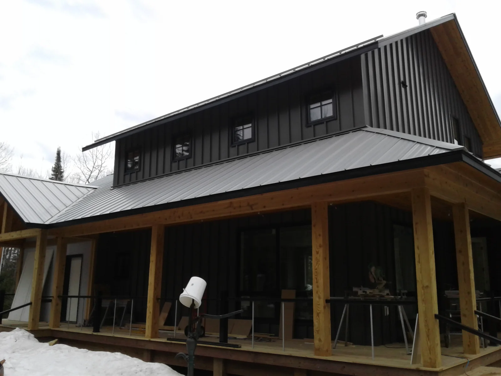 Close look at the dark metal roof and screened porch on the contemporary cabin