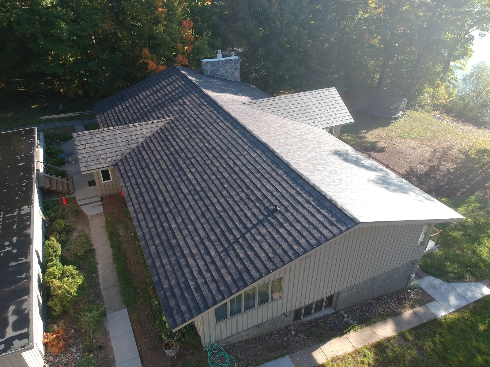 Wide angle of the long gray-roofed home with its walkway and surrounding lawn.