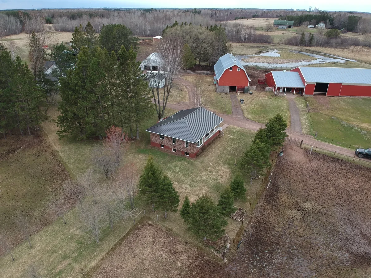 Aerial of a brick rambler with a dark gray hip-style metal roof on a rural lot in Mankato, MN