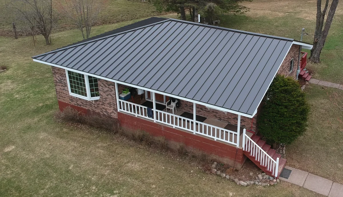 Drone view of the charcoal standing seam roof over the brick home and front porch