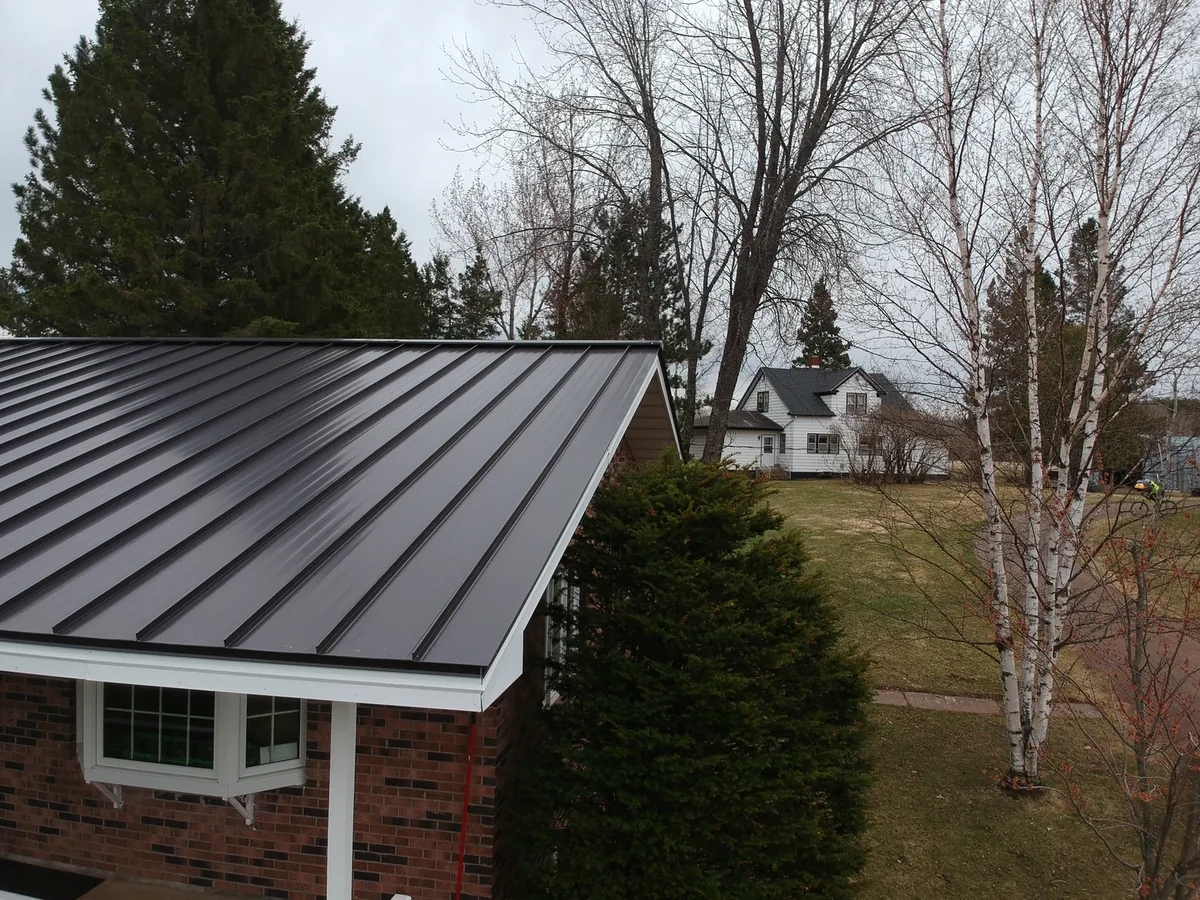 Close detail of the dark metal roof edge and white trim over the brick siding