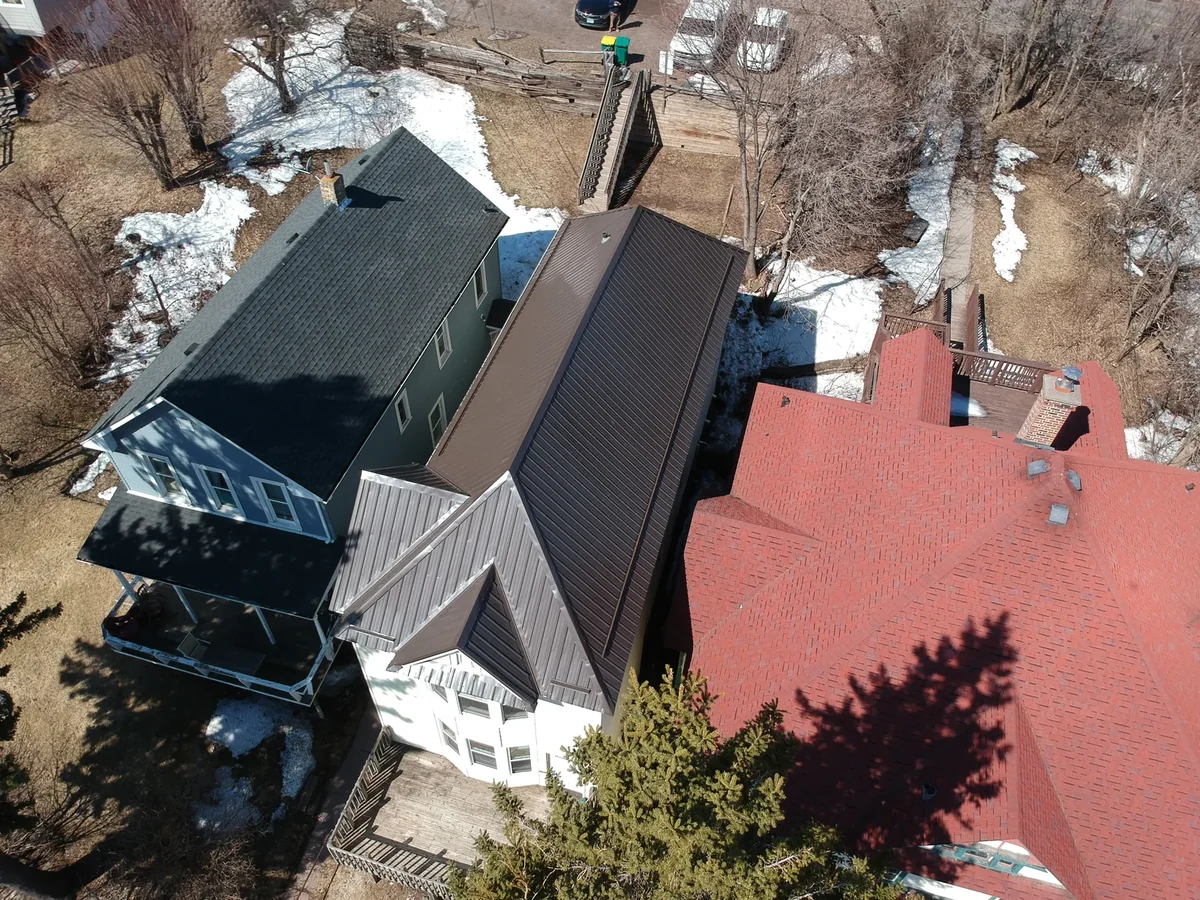 Aerial view of a multi-gable home with a Patrician Bronze exposed-fastener metal roof in a dense Minneapolis, MN neighborhood