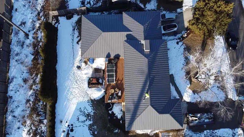 Overhead aerial of a dark standing seam metal roof on a snow-covered home in Minnetonka, MN.