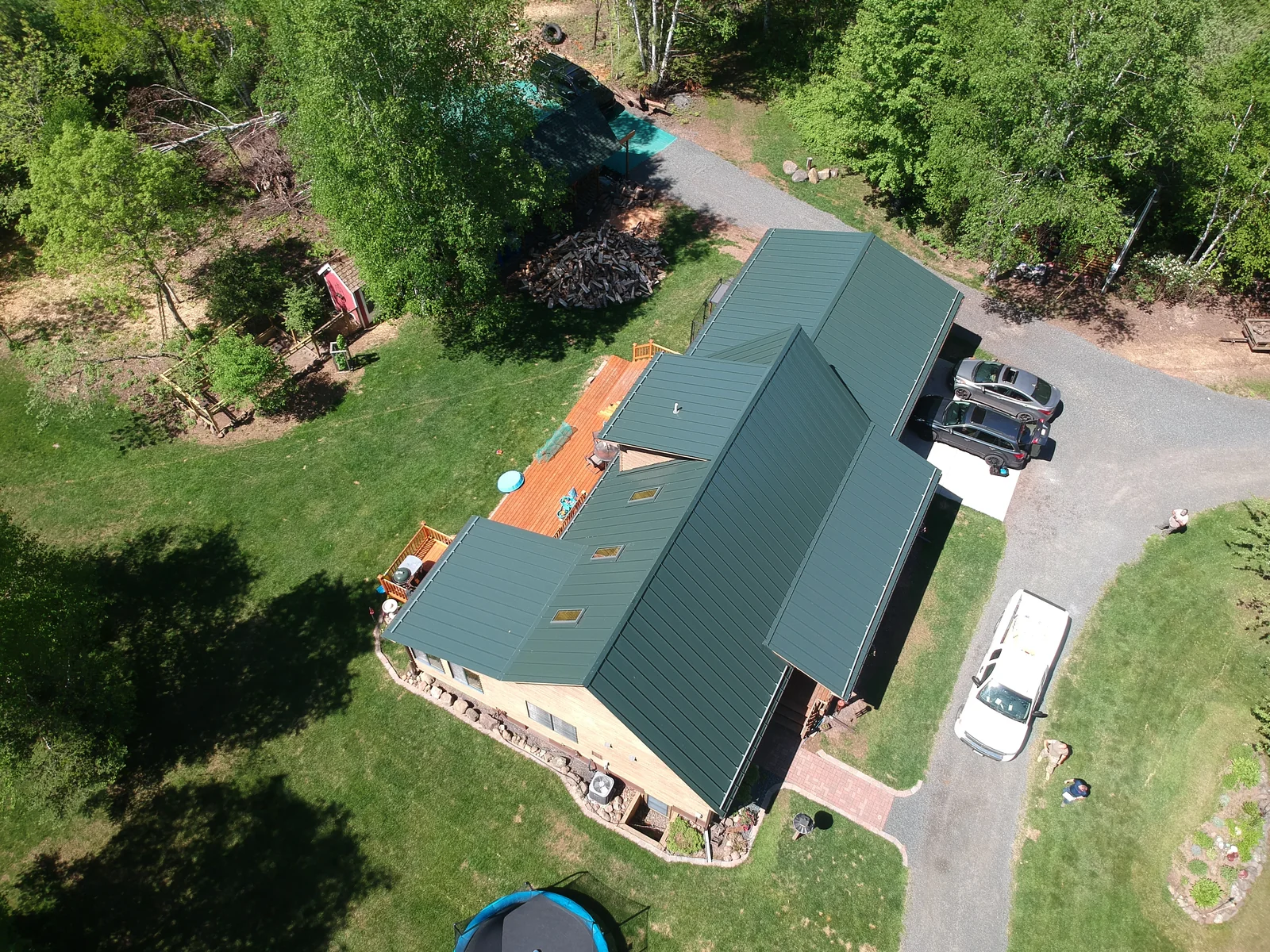 Drone shot of the evergreen metal roof over the log home and gravel drive