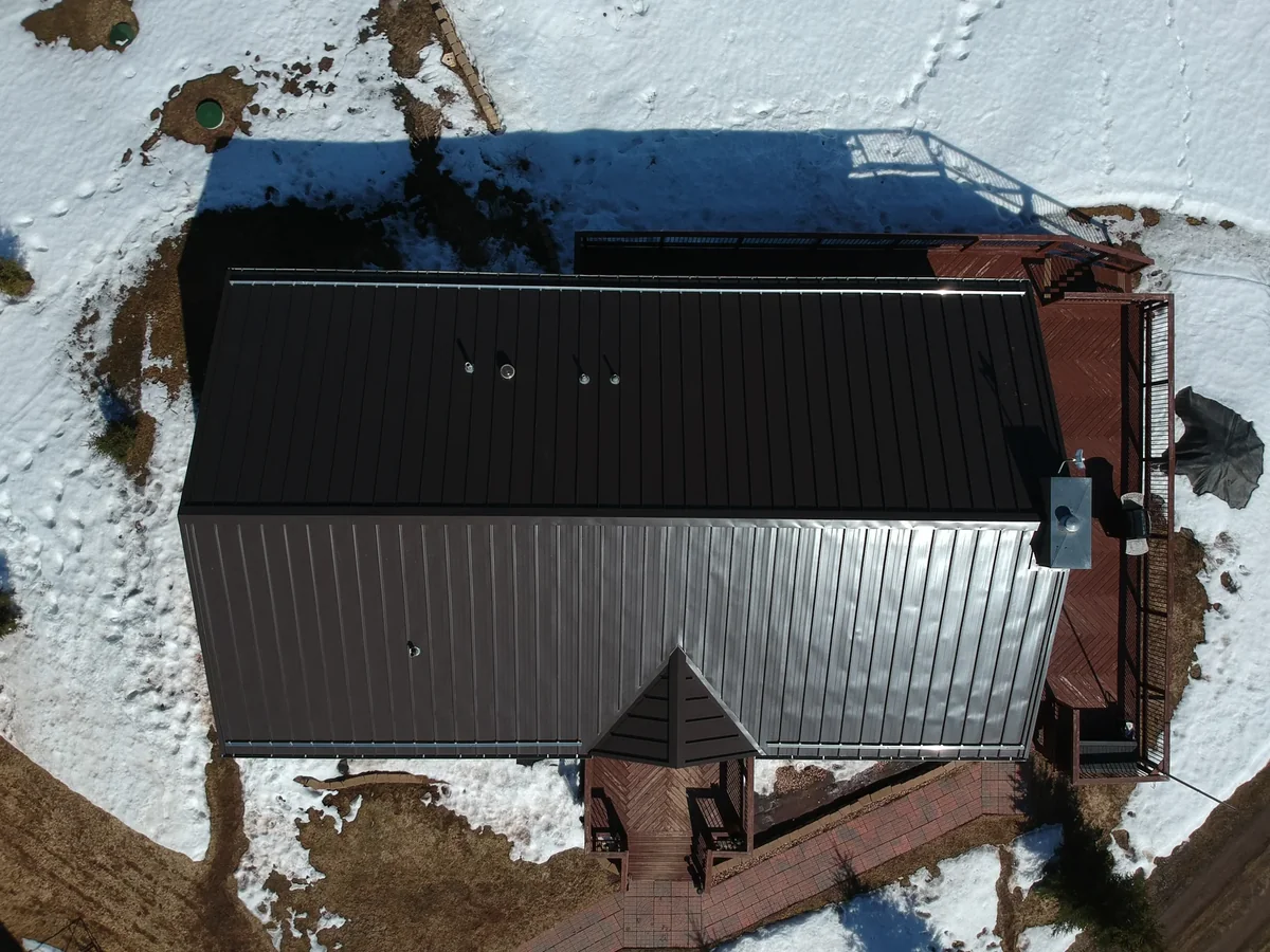 Overhead view of the dark bronze metal roof with a small cupola and snowy yard below.