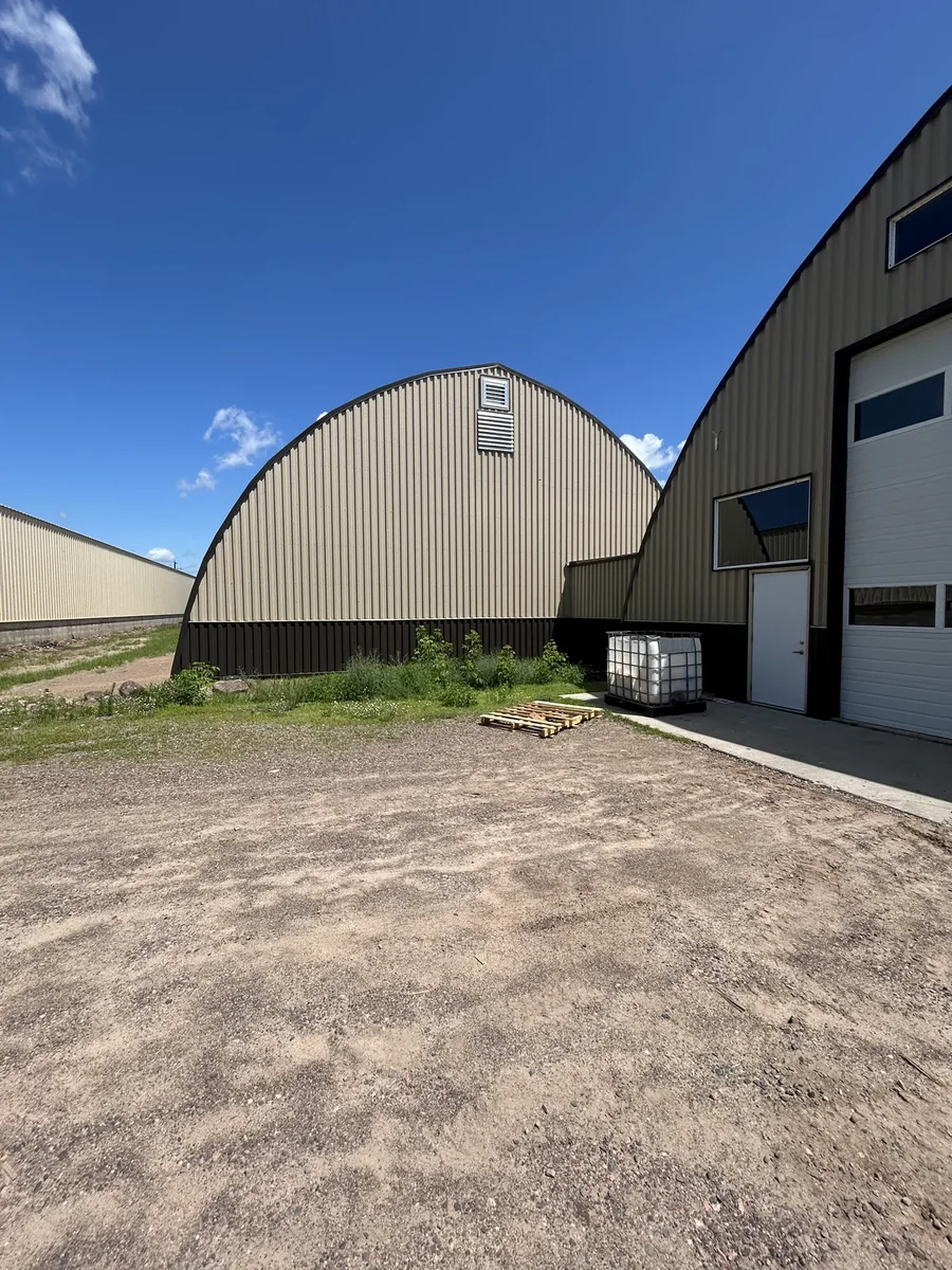 End elevation of the arched building showing the metal end wall and adjoining garage doors