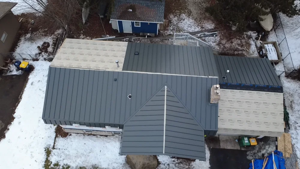 Aerial view of a long single-story home with a gray standing seam metal roof in a snowy yard in Rosemount, MN