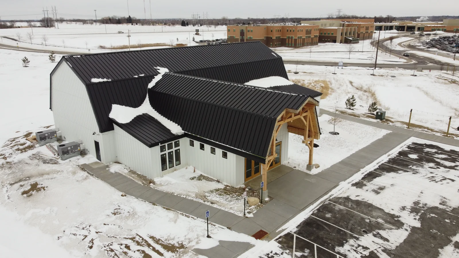 Drone angle of the commercial complex's charcoal metal roofs and heavy timber entry beams.