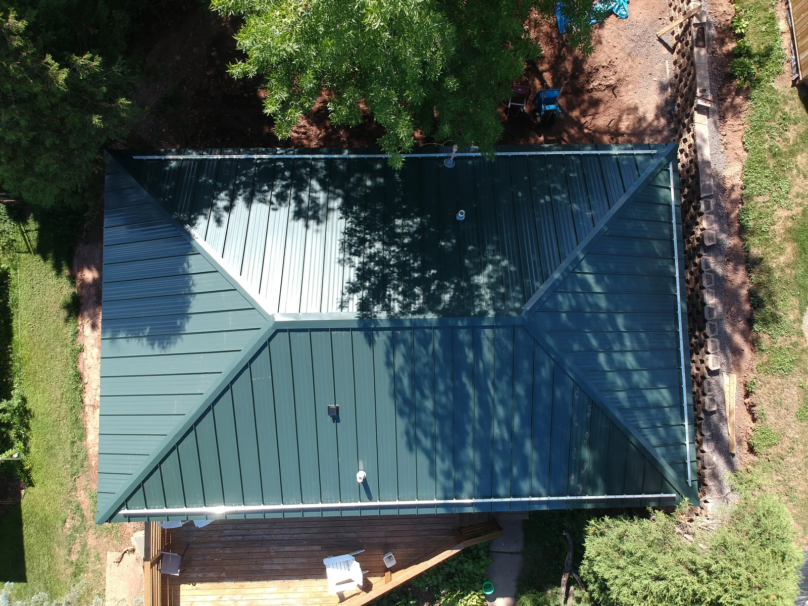 High overhead detail of the dark green standing seam hip roof and its crisp ridge lines