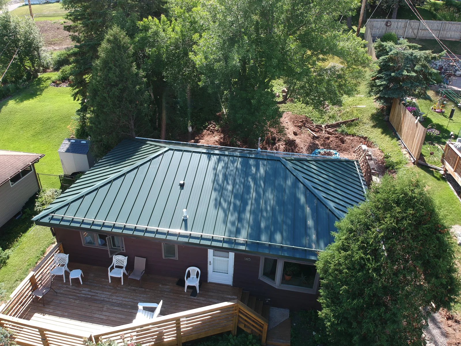 Side view of the deep green metal roof overlooking the patio and deck furniture
