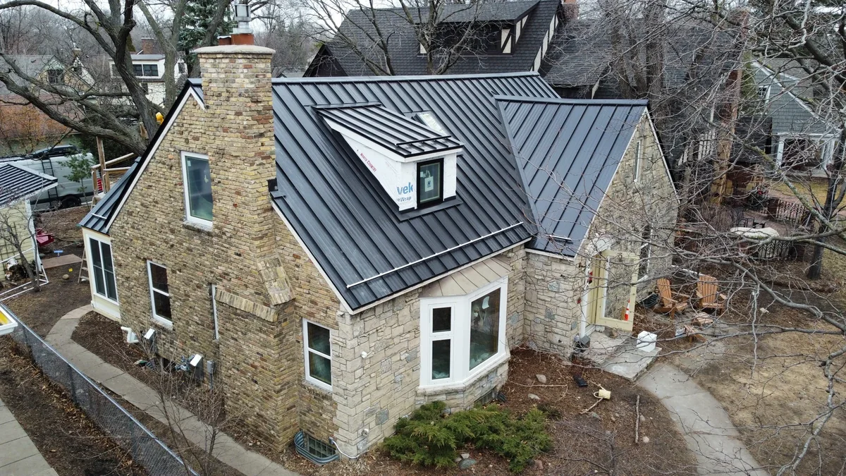 Aerial view of a stone house in St. Paul, MN with a charcoal grey standing seam metal roof