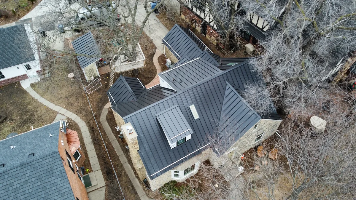 Overhead view of the grey standing seam roof and the surrounding bare-branched yard