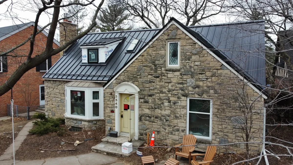 Angled aerial of the grey metal roof above the stone walls and arched entry