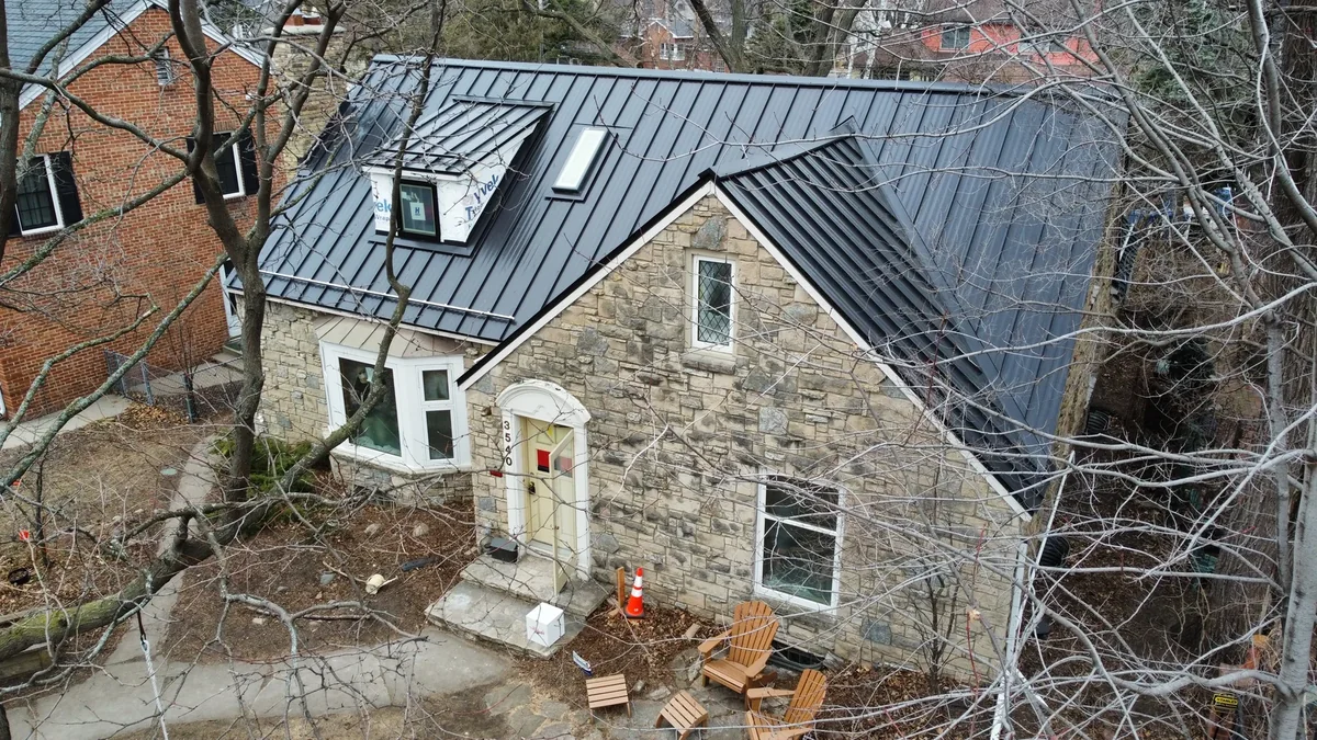 Close aerial of the grey metal roof gables meeting over the stone facade