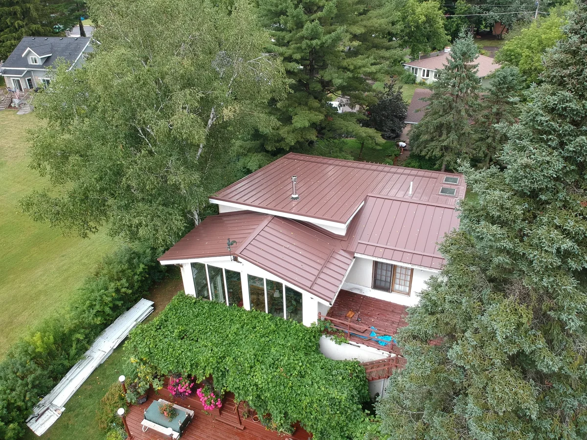 Side angle of the home showing the brown standing seam roof over white walls.
