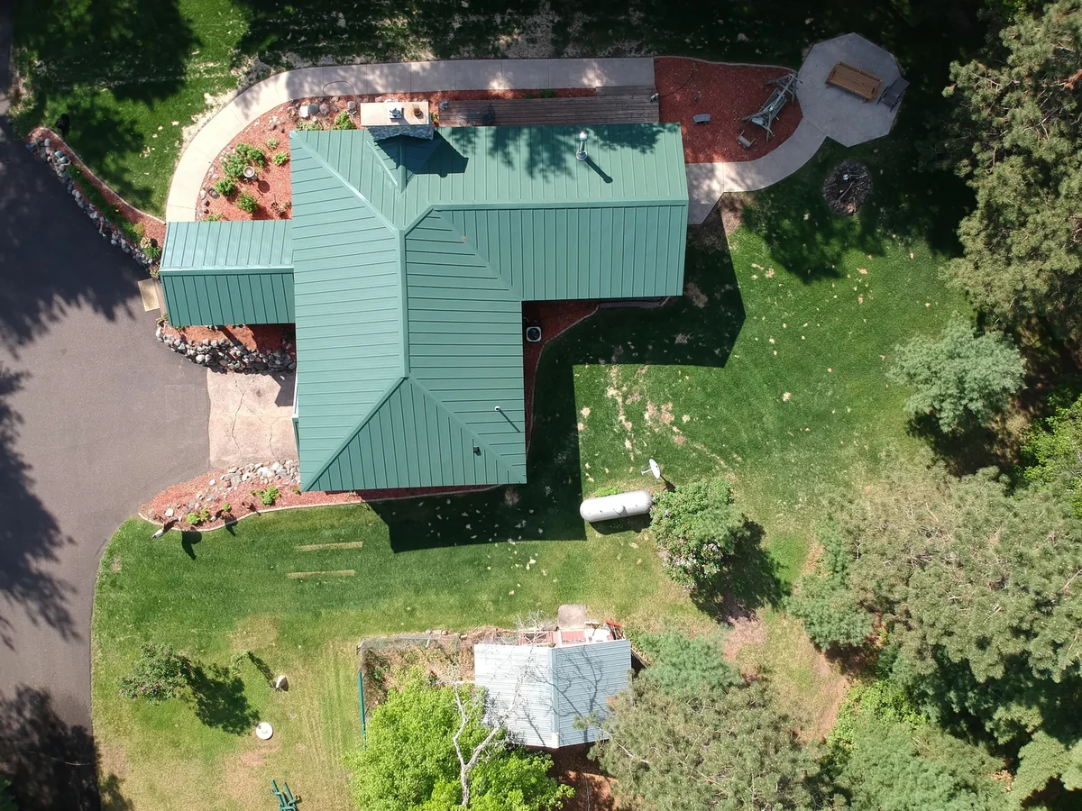 Top-down view of the green metal roof and the landscaped grounds around the residence.