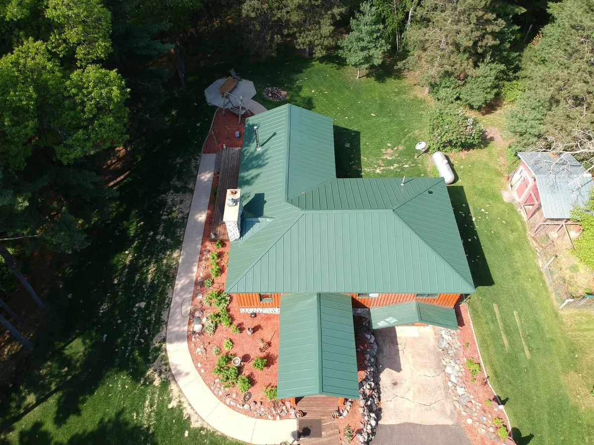Wide drone shot of the green-roofed estate nestled among the trees.