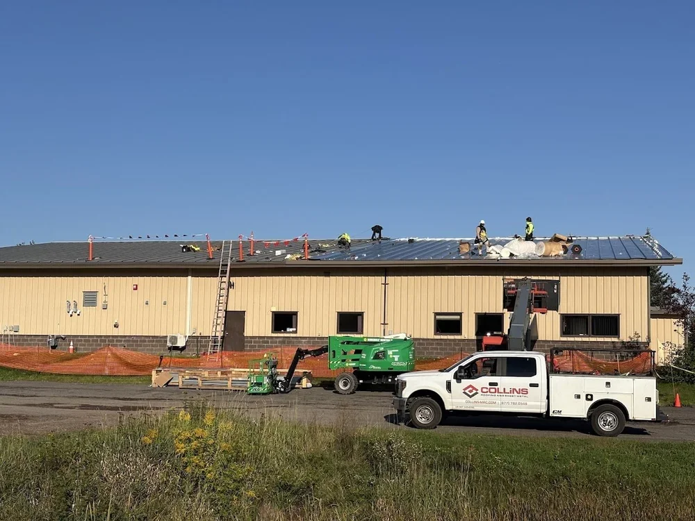 Long building in the Twin Cities mid-installation of a copper metal recover roof with a work truck and lift on site