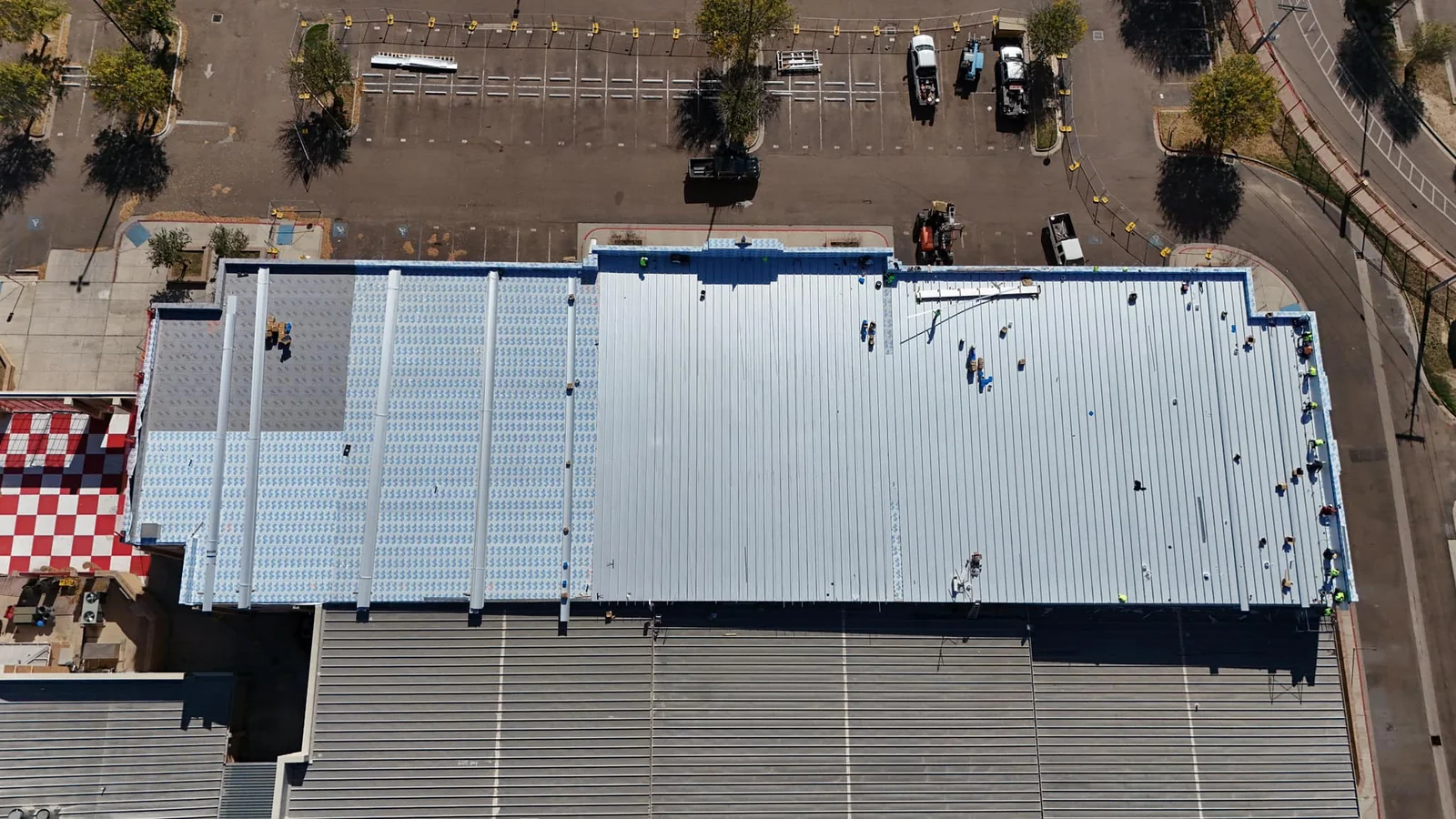 Aerial of a long commercial building mid-recover with a new standing seam metal roof in the Twin Cities.