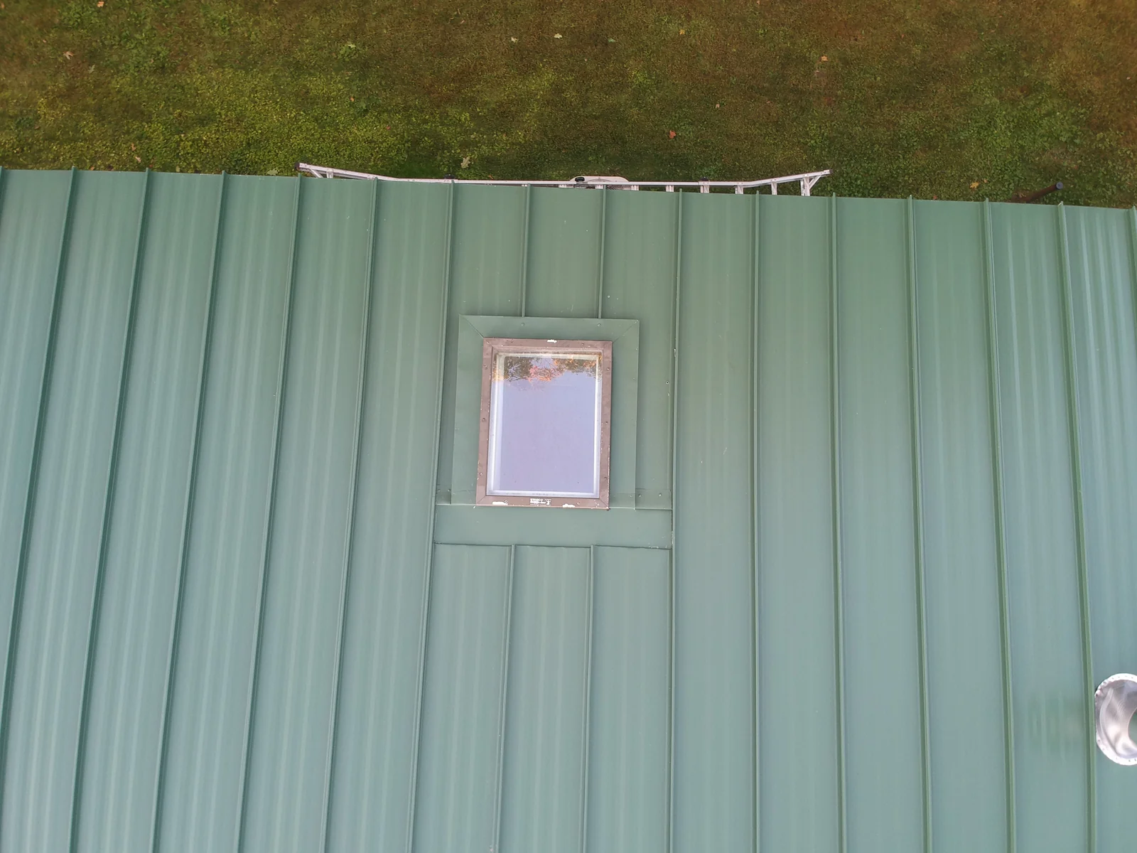 Close overhead detail of the green standing seam panels around a roof skylight.