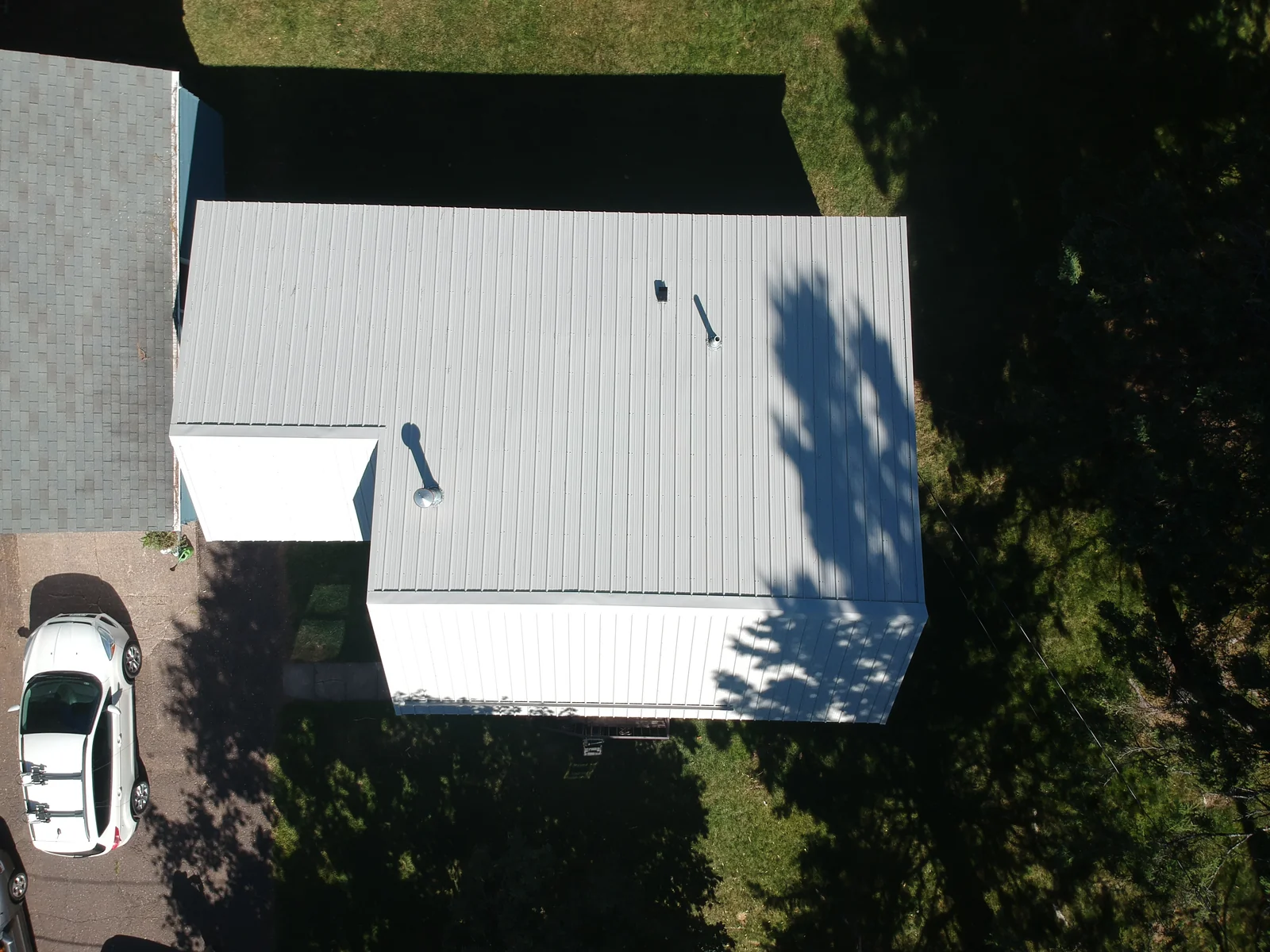 Drone shot of the light gray standing seam roof over the home and attached garage