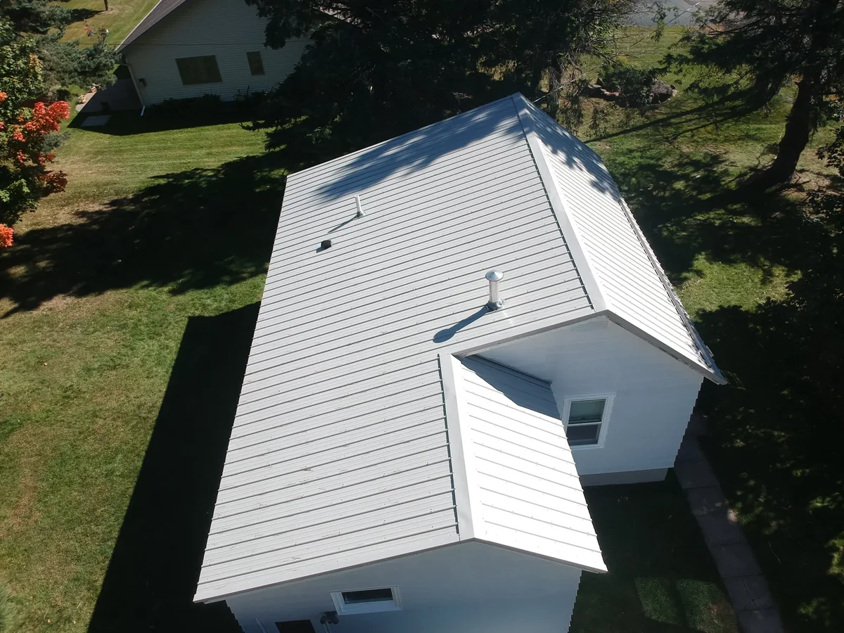 Angled aerial of the silver metal roof and its gables among the trees