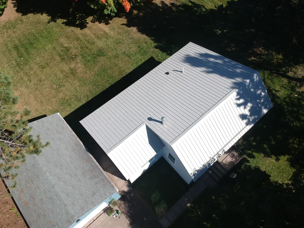 Overhead view of the metallic standing seam roof next to a darker neighboring roof