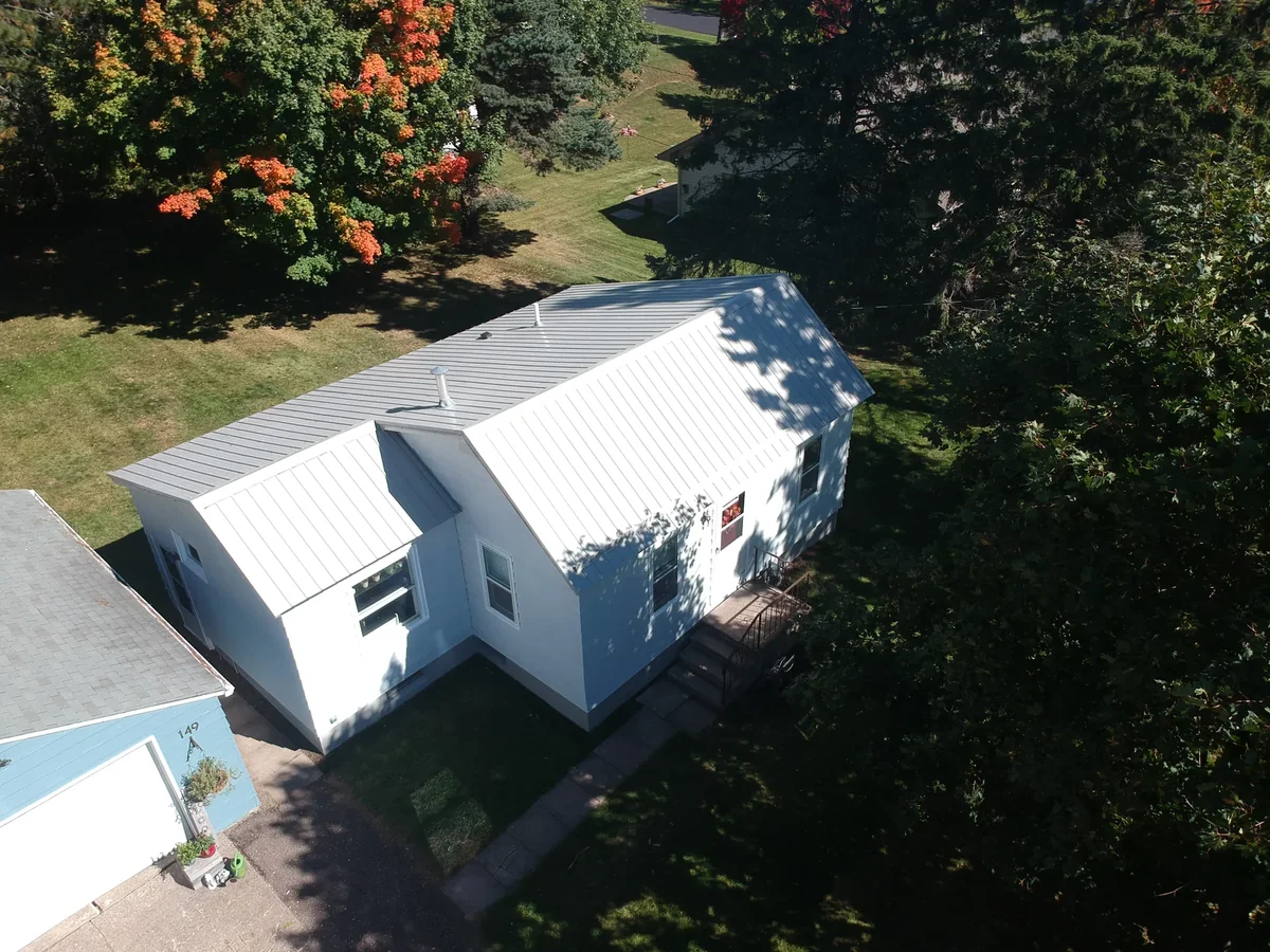 High view of the bright metal-roofed home framed by autumn foliage