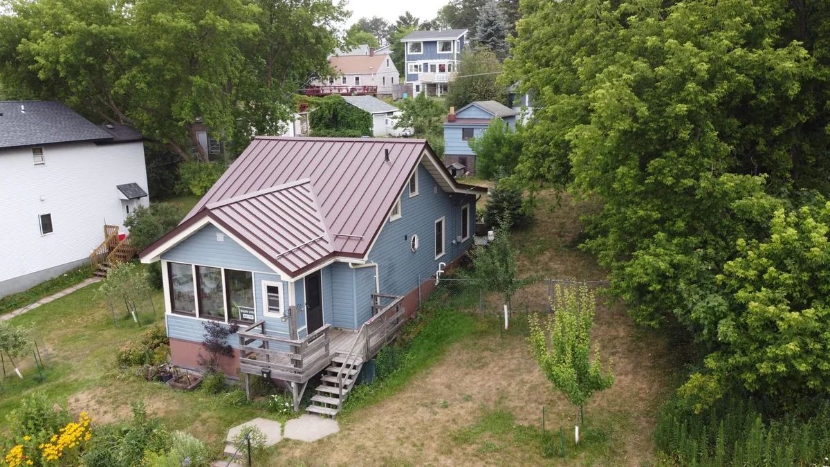 Front view of the bungalow showing the mauve metal roof above the screened porch